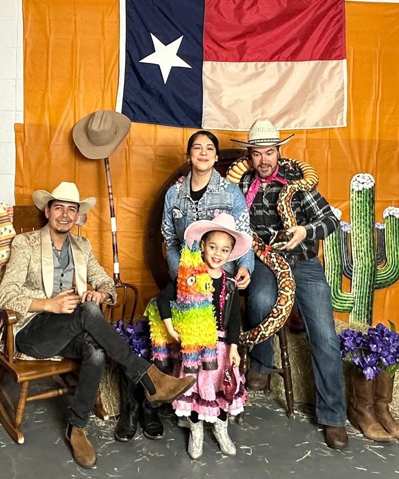 Cowboy family with colorful piñata, Texas flag